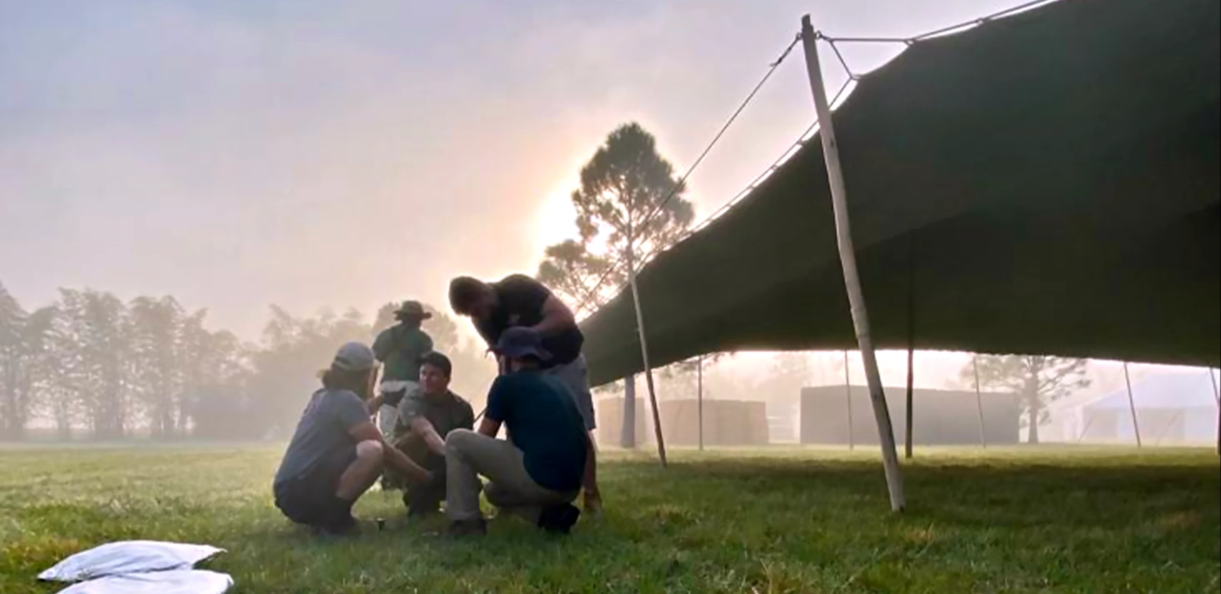 Stretch tent anchoring stakes being installed on grass at an outdoor event